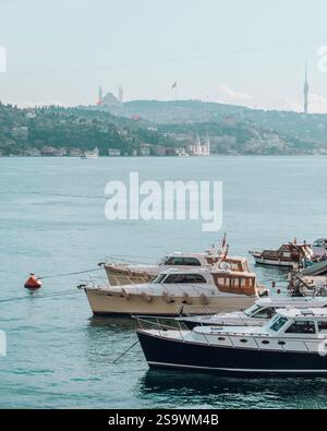 Ruhige Fotografie von Booten, die auf der Bosporusstraße in Istanbul schwimmen, mit der berühmten Skyline der Stadt im Hintergrund. Stockfoto