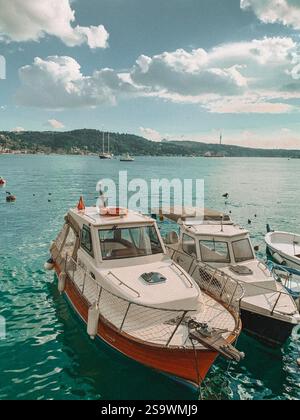 Ruhige Fotografie von Booten, die auf der Bosporusstraße in Istanbul schwimmen, mit der berühmten Skyline der Stadt im Hintergrund. Stockfoto