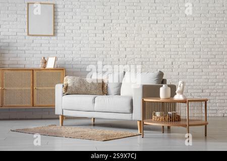 Gemütliches graues Sofa mit Couchtisch vor dem Fenster im Wohnzimmer Stockfoto