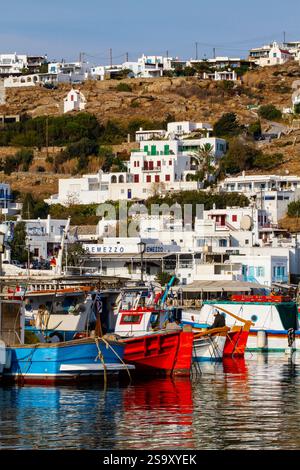 Mykonos, Griechenland. Blaue, rote und gestreifte Holzboote Fischerboote und Dorf an der Bucht Stockfoto