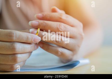 Scheidungskonzept. Frau, die den Ehering abzieht und Scheidungspapiere unterschreibt. Nahaufnahme, selektiver Fokus. Stockfoto