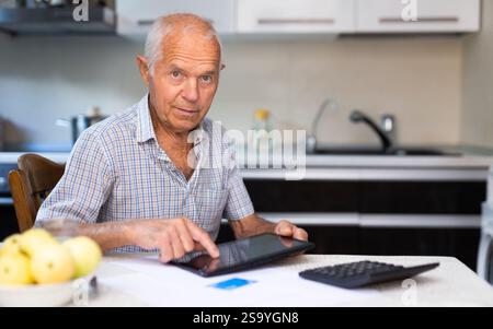 Ein alter Mann, der Online-Einkäufe über ein Tablet macht Stockfoto