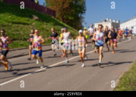 Ein unfokussiertes Hintergrundbild einer Gruppe von Athleten, die an einem Marathon durch die Straßen einer Stadt teilnehmen. Eine Gruppe Männer, die in einem Ro laufen Stockfoto