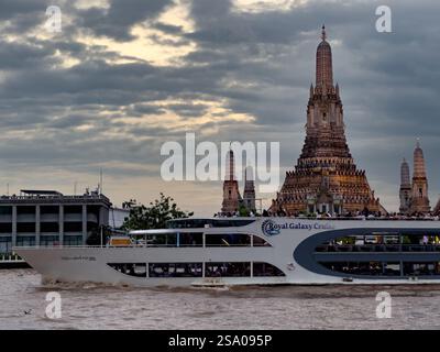 Ein beeindruckender Blick auf Wat Arun, den Tempel der Dämmerung, mit dem Royal Galaxy Cruise Boot im Vordergrund. Der zentrale Prang des Tempels steht hoch unter einem d Stockfoto
