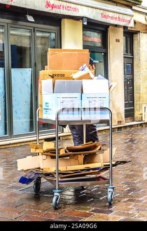 Junge Frau, die mit Abfallkartons beladene Rollwagen zieht - Tours, Indre-et-Loire (37), Frankreich. Stockfoto