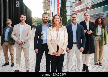 Verschiedene Gruppe von professionellen Einzelpersonen, die sich in stilvoller Kleidung für ein Unternehmensprofil in einem Bürogebäude mit Ausblick auf ihre Zukunft und gemeinsamen Bemühungen um Erfolg ausgeben. Hochwertige Fotos Stockfoto