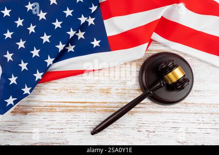 Der Hammer des Richters und die amerikanische Flagge auf weißem Holztisch, Blick von oben. Stockfoto