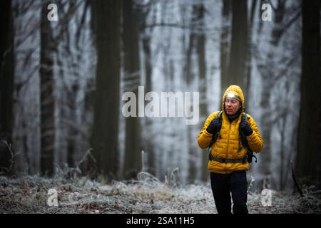 Winterwandern im Wald. Mann mit Scheinwerfer, der durch dunkle, frostige Wälder geht. Outdoor-Abenteuer Stockfoto