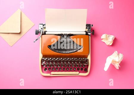 Vintage-Schreibmaschine, zerknittertes Papier und Umschlag auf rosafarbenem Hintergrund, flach Stockfoto