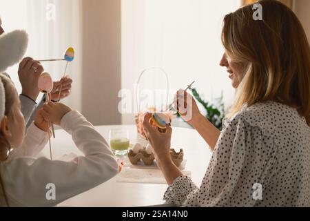 Familie malt gemeinsam Ostereier an einem gemütlichen Tisch mit festlicher Atmosphäre Stockfoto