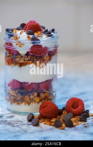 Mehrschichtiges Frühstück mit Joghurt, Beeren und Crumble in einem kleinen Glas Stockfoto