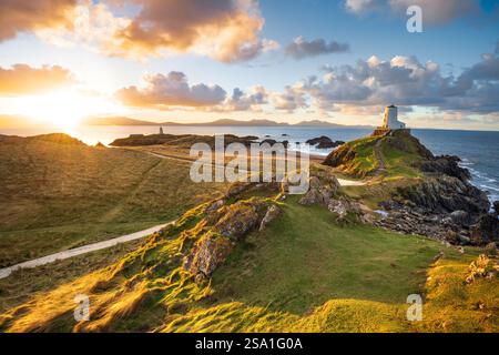 TWR Mawr Lighthouse auf Ynys Llanddwyn Island an der Küste von Anglesey, Nordwales mit Snowdonia Mountains im Hintergrund. Stockfoto