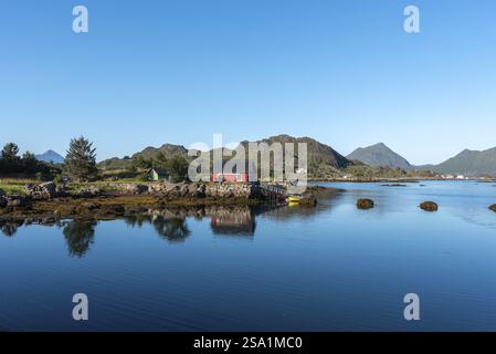 Blick über die Landschaft der Bucht von Skotnesosen mit einem traditionellen roten Fischerhaus, genannt Rorbu, Ballstad, Lofoten, Norwegen, Europa Stockfoto