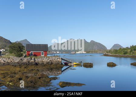 Blick über die Landschaft der Bucht von Skotnesosen mit einem traditionellen roten Fischerhaus, genannt Rorbu, Ballstad, Lofoten, Norwegen, Europa Stockfoto