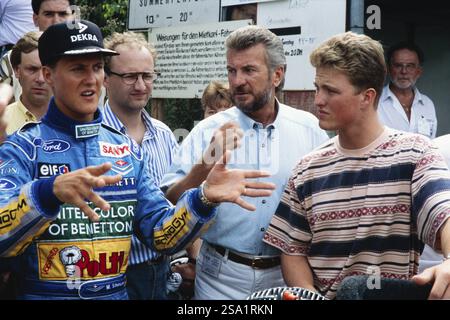 Formel-1-Fahrer Michael Schumacher im blauen Rennanzug spricht mit seinem Manager Willi Weber (Mitte) und seinem Bruder Ralf Schumacher (rechts), hier VI Stockfoto
