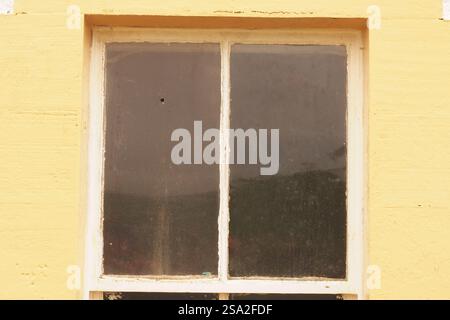 Ein altes Fenster mit einem Luftgewehrloch in einer seiner Scheiben Stockfoto