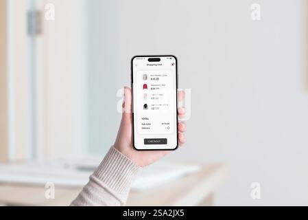 Smartphone-Bildschirm mit einem Einkaufswagen mit Kleidungsstücken, dem Gesamtpreis und der Schaltfläche „Checkout“ unten in einer modernen App Stockfoto