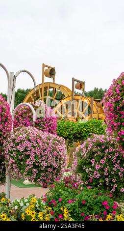 Blumentöpfe mit frischen Blumen rosa Petunien und Wassermühle in Dubai, Vereinigte Arabische Emirate. Vertikales Bild. Stockfoto