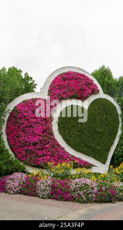 Figur in Form von zwei Herzen aus lebenden rosa Petunienblüten im Wundergarten in Dubai, Vereinigte Arabische Emirate. Vertikales Bild. Stockfoto