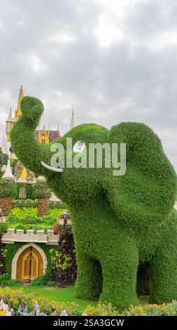 Eine topiäre Figur in Form eines Elefanten aus grünem Rasengras und Märchenschloss der Prinzessin im Wundergarten in Dubai, Vereinigte Arabische Emirate. Vertikal Stockfoto