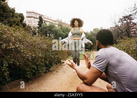 Ein männlicher Fitnesstrainer beaufsichtigt eine Frau, die mit einem Sprungseil in einem Park trainiert, um Outdoor-Fitness und einen aktiven Lebensstil zu fördern. Stockfoto