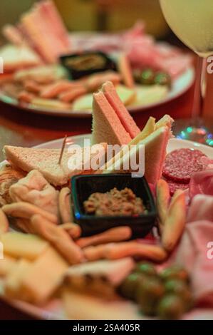 Eine vertikale Aufnahme einer Platte mit verschiedenen Käsesorten, Salami und anderen Speisen Stockfoto