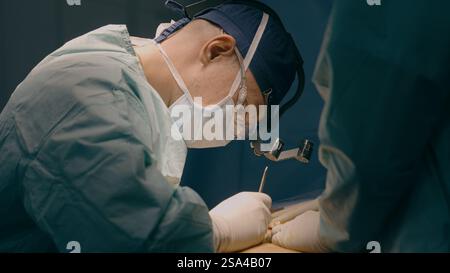 Arzt Mann in Uniform Arzt Chirurg medizinische Krankenschwester, die chirurgische Operation an der Klinik Plastische Chirurgie Mikrochirurgie rettet Leben Patient Stockfoto