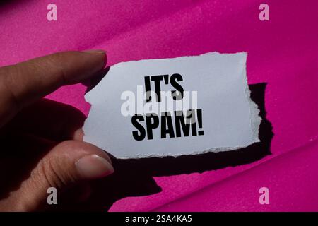 Es ist eine Spam-Nachricht auf zerrissenem Papier mit rosa Hintergrund. Konzeptionell ist das Spam-Symbol. Kopierbereich. Stockfoto
