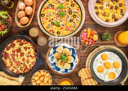 Eine Auswahl an köstlichen Eierspeisen aus dem Nahen Osten. Serviert mit frischem Orangensaft, Brot, grünem Salat, Gurken und Kartoffelwürfeln. Draufsicht mit Nahaufnahme Stockfoto