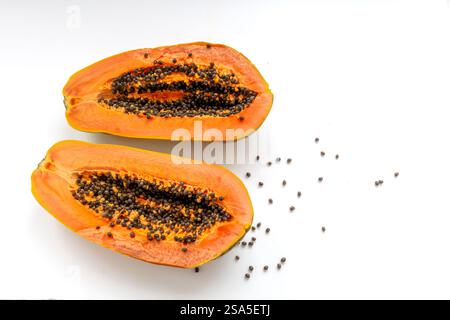 Flache Lagen von zwei Hälften einer Reifen Papaya, die das süße, leckere orangene Fleisch und schwarze Samen auf weiß freilegen. Stockfoto