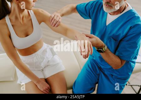 Hochwinkelaufnahme eines hochqualifizierten Arztes, der Bizeps einer Patientin während des Termins untersucht Stockfoto