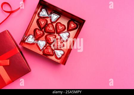 Herzförmige Pralinen in roter Geschenkbox mit rosafarbenem Hintergrund, Süßigkeiten zum Valentinstag Stockfoto