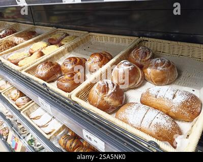 Verschiedene frische Gebäckstücke in Korbkörben auf dem Backwarenregal. Stockfoto