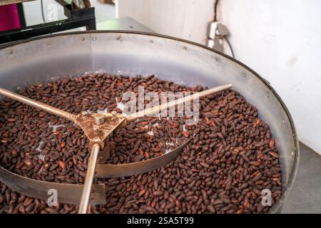 Bali, Indonesien: Nahaufnahme einer Röstmaschine mit Kakaobohnen während des Kakaoröstvorgangs in einer Fabrik. Stockfoto