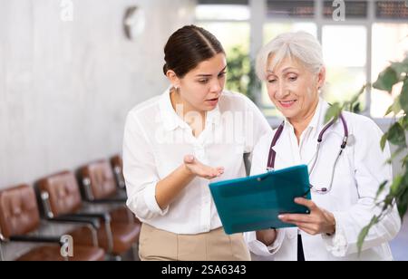 Aufmerksame leitende Ärztin verschreibt Tests an Patienten der Klinik, um den Gesundheitszustand zu überprüfen Stockfoto