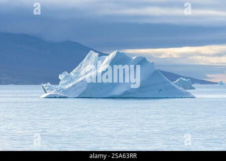 Große Eisberge schweben in der Abendsonne, dahinter Berge der Geeenländischen Küste. . Sullorsuaq-Straße, Westgrönland, Dänemark, Nordamerika Stockfoto