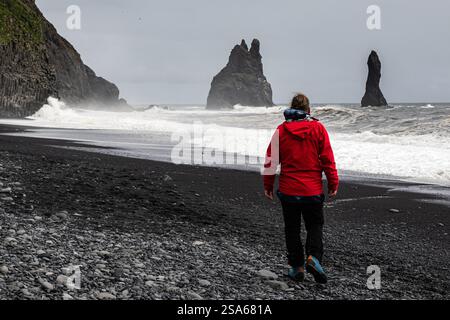 Reisende spazieren an einem majestätischen schwarzen Sandstrand Reynisfjara in Island im VIK Myrdal im Golden Circle Gebiet in der Nähe des Atlantischen Ozeans große Wellen Stockfoto