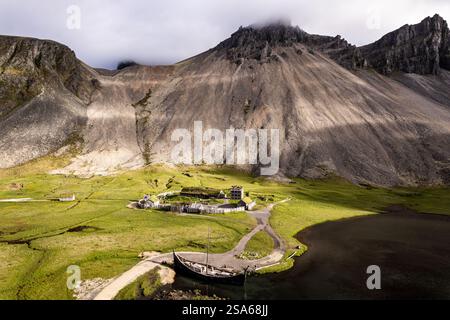 Ein malerischer Blick auf ein grünes Tal mit einem Wikingerdorf, umgeben von den majestätischen Vestrahorn Bergen in Stokksnes in Island. Eine ruhige Atmosphäre Stockfoto