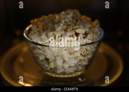 Schüssel mit leckerem Popcorn in der Mikrowelle, Nahaufnahme Stockfoto