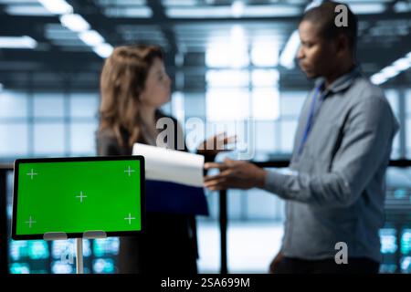Mockup-Tablet, das von Technikern im Rechenzentrum im unscharfen Hintergrund zur Überprüfung der Hardwarediagnose verwendet wird. Nahaufnahme eines Geräts mit isoliertem Bildschirm, das von Mitarbeitern verwendet wird, die Gerätekonfigurationen anpassen Stockfoto