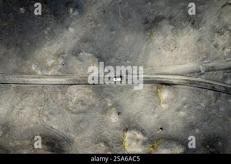 Drohnenansicht eines weißen Autos, das auf einer abgelegenen Wüstenstraße auf der Straße zum Campingplatz Thakgil (Pakgil) in der Nähe von Vik in Island fährt Stockfoto