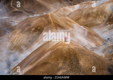 Panoramablick auf einen Wandermann in roter Jacke und den nebligen Kerlingarfjoll-Bergpfad inmitten von Wüste und schneebedecktem Gelände in Island Stockfoto