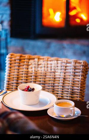 Frischer Kaffee und Nachtisch werden im Restaurant mit Kamin im Hintergrund serviert Stockfoto