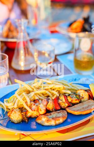 Nahaufnahme von Hähnchenspießen und Pommes Frites, die zum Mittagessen in einem Restaurant serviert werden Stockfoto
