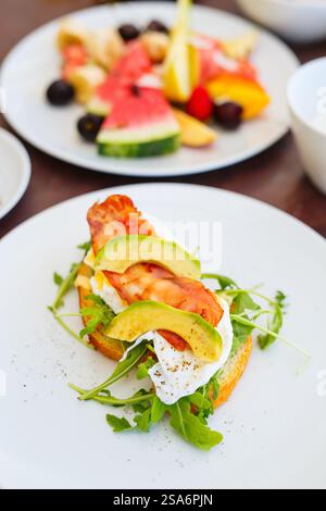 Köstliches Benedict-Frühstück mit Avocado und Speck im Restaurant Stockfoto