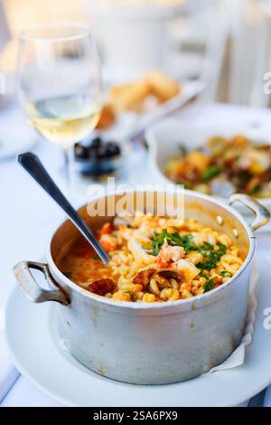 Köstliche Pasta mit Meeresfrüchten, serviert mit Weißwein zum Mittag- oder Abendessen im Restaurant Stockfoto