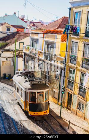 Alte gelbe Straßenbahn in ruhiger Straße im Alfama-Viertel im Zentrum von Lissabon in Portugal mit farbenfrohen Haus bedeckt mit traditionellen portugiesischen Fliesen Azulejo Stockfoto