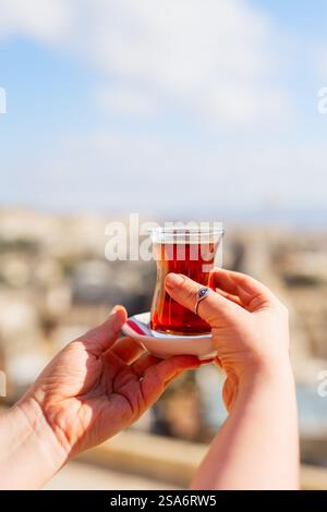 Türkischer Tee in einem traditionellen Glas in der Hand Stockfoto