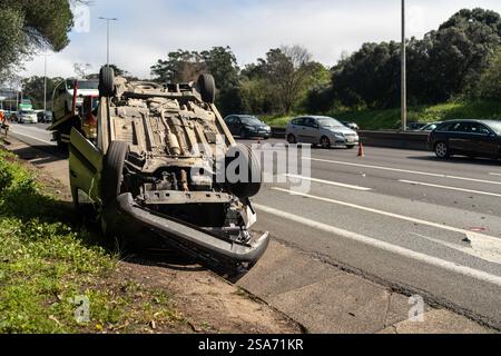 Beschädigtes Fahrzeug nach einer Kollision, die kopfüber auf der Straße lag. Geschäftige Stadtstraße mit Auto, das tagsüber überfahren wurde. Autounfall Stockfoto