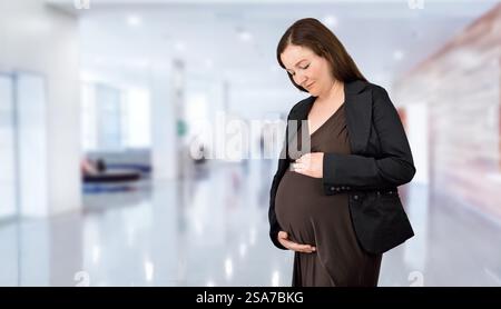 Schuss einer schwangeren Geschäftsfrau, die in ihrem Büro steht und ihren Magen hält Stockfoto